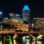 Vista noturna da baía de Marina Bay, em Singapura, com a Esplanada e edifícios iluminados ao fundo.