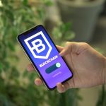Mão segurando um smartphone com um aplicativo de blockchain exibido na tela