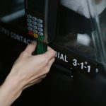 Pessoa paga uma corrida de táxi aproximando um cartão de um dispositivo de pagamento dentro do veículo.