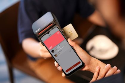 Smartphone sendo aproximado de um terminal para realizar pagamento por aproximação via NFC
