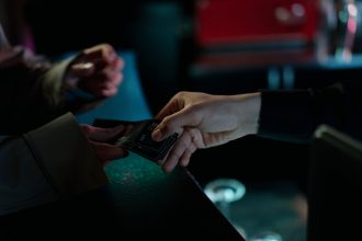 Mãos trocando ingressos de cinema em um ambiente interno
